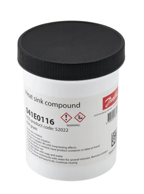 Weißer Behälter mit schwarzem Deckel, beschriftet mit Warnhinweisen und Anwendungshinweisen. Enthält Wärmeleitpaste von Danfoss.